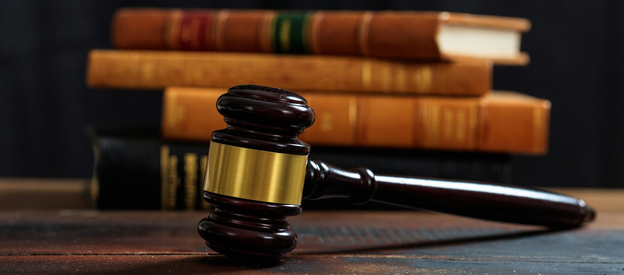 Judge gavel on a wooden desk, law books background